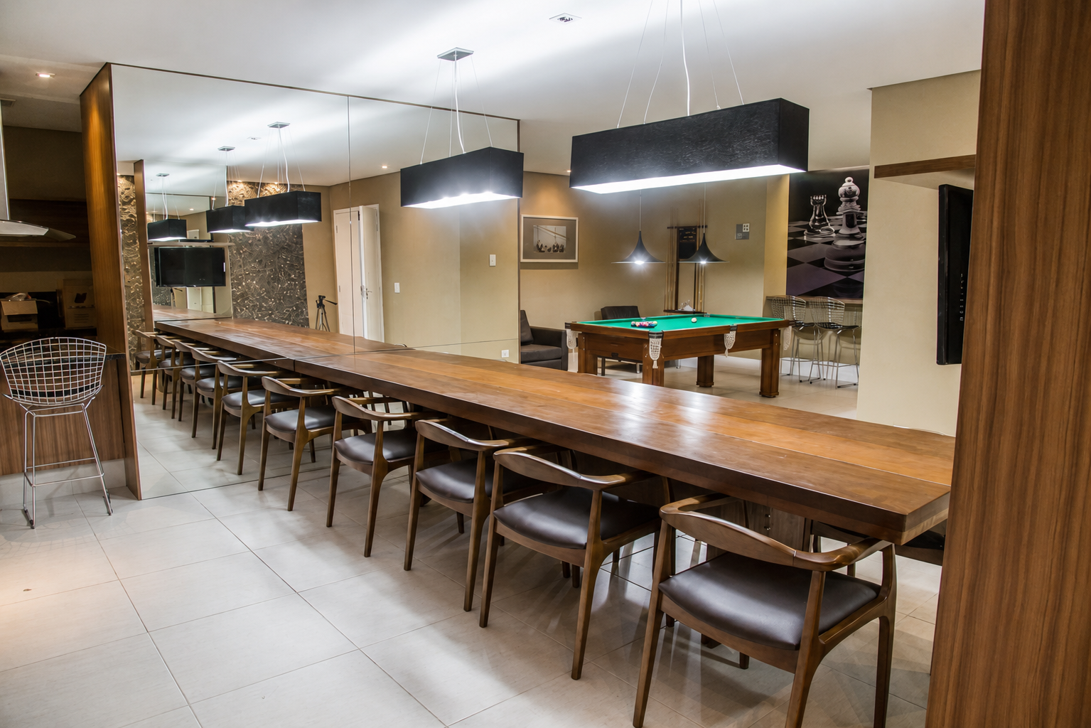 Espaço de convivência com mesa longa, cadeiras e mesa de jogos