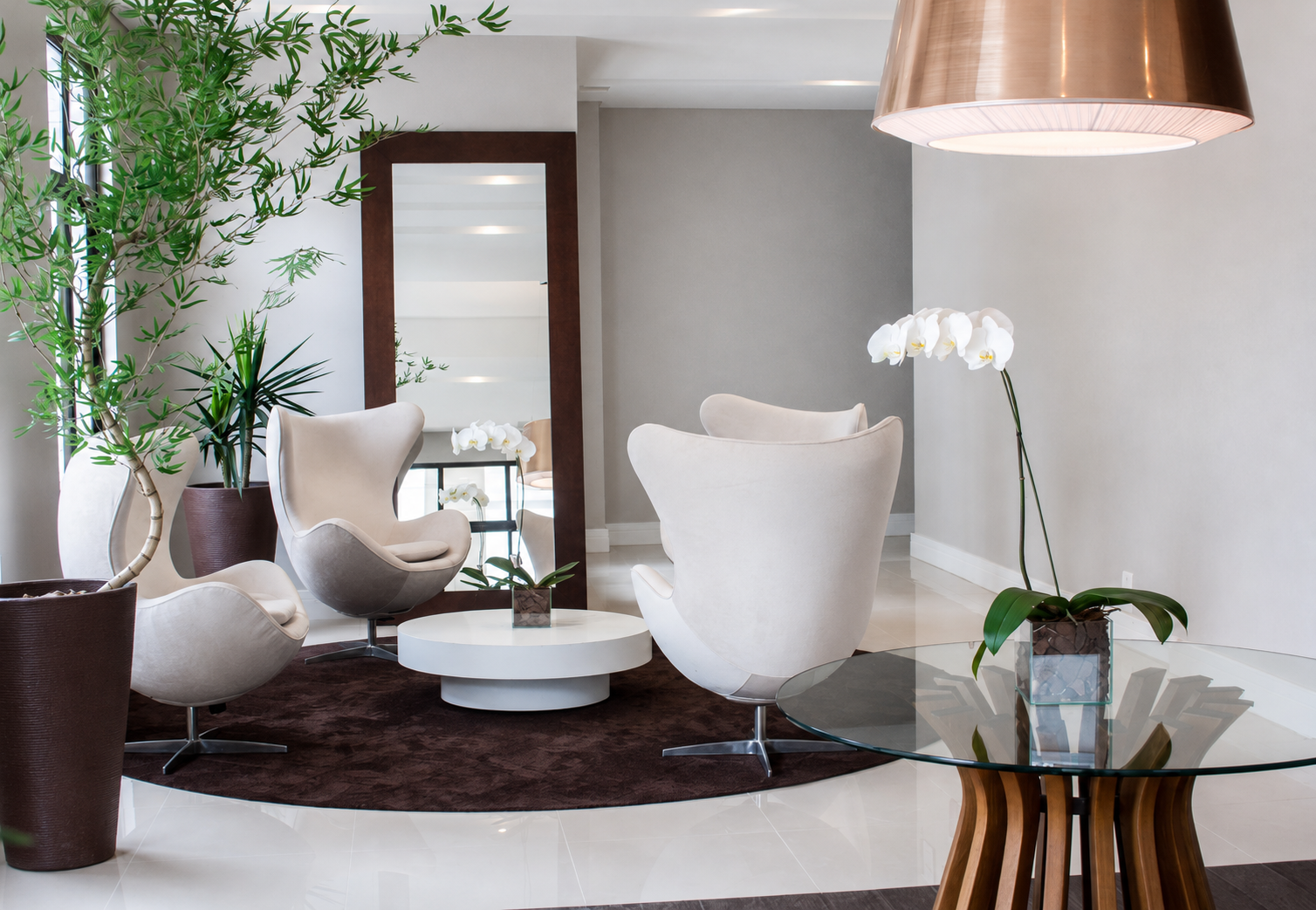 Recepção com poltronas, mesa central e vegetação