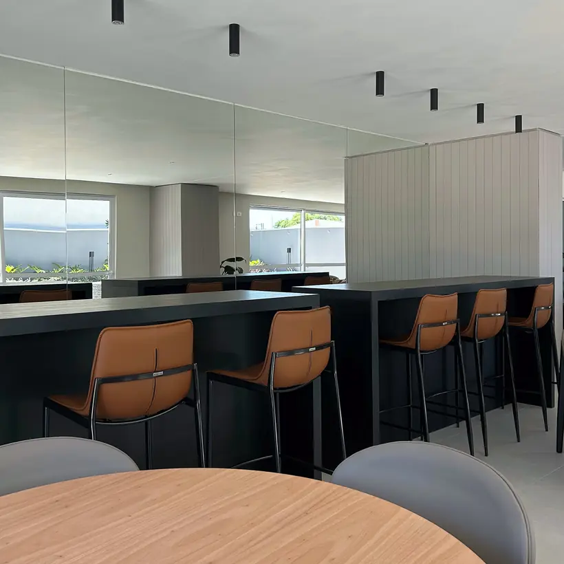 Espaço colaborativo com bancadas, espelhos e banquetas em couro