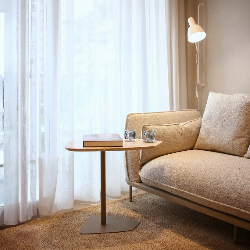 Detalhe de sofá, mesa lateral e iluminação junto à janela