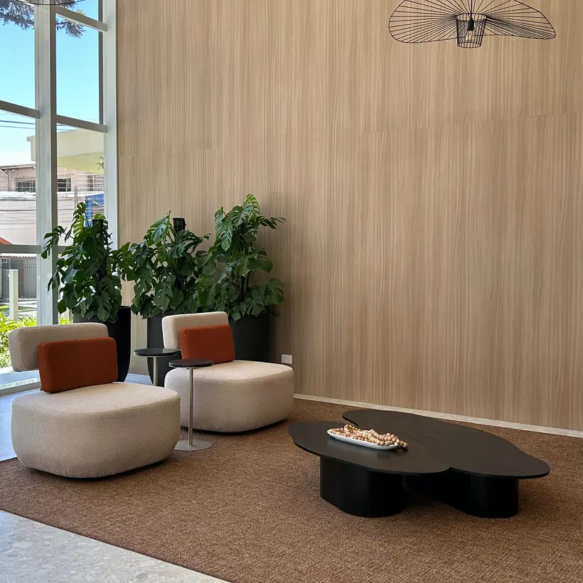 Lounge de recepção com poltronas curvas e mesas em madeira escura